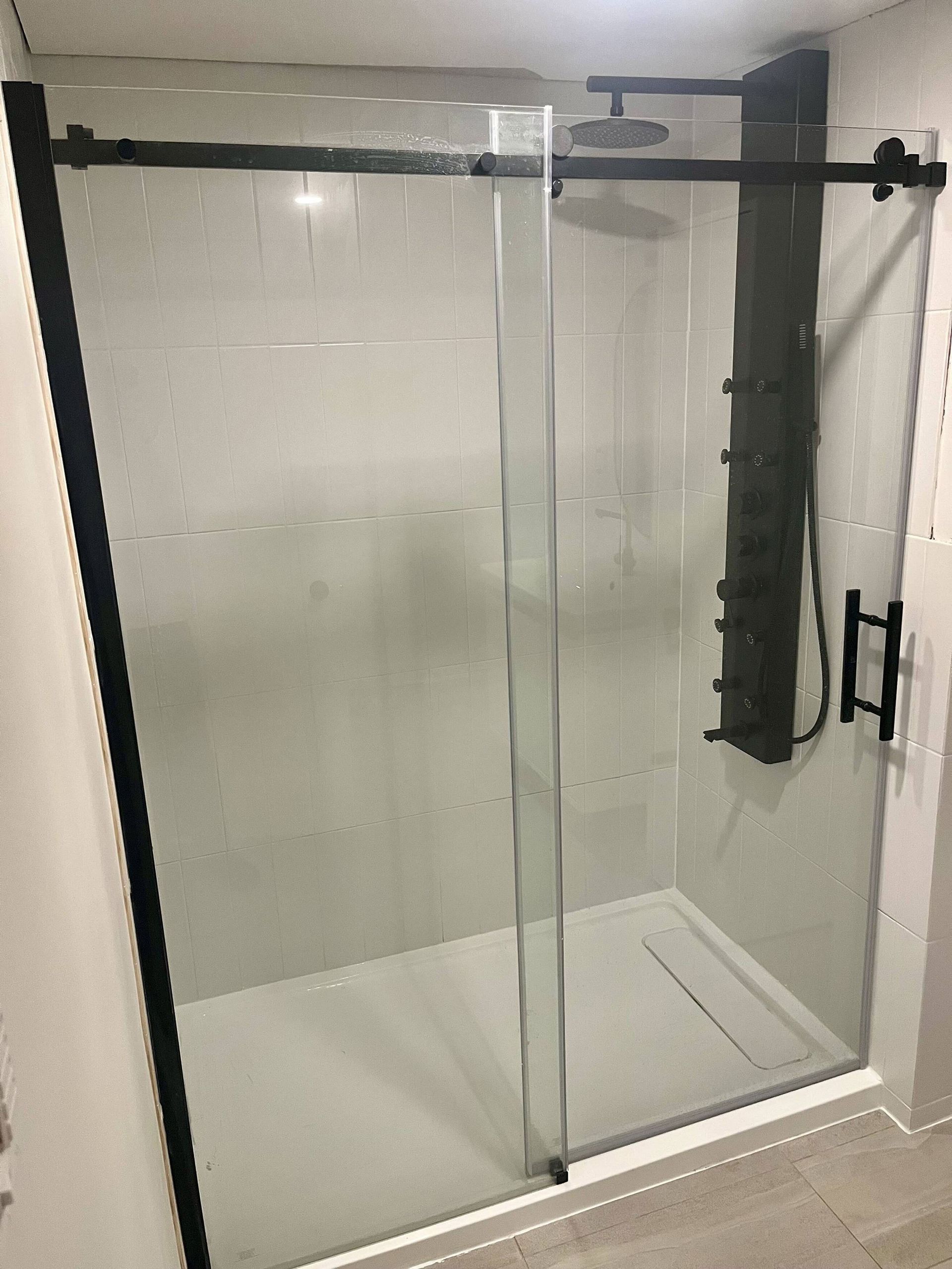 Une salle de bain avec une porte de douche coulissante en verre et une pomme de douche.