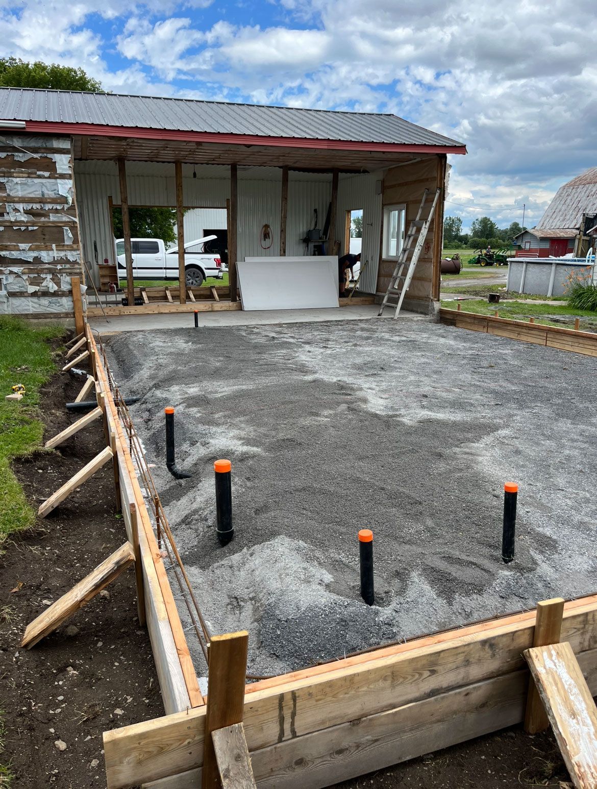 Une maison est en cours de construction sur un terrain en terre avec des fondations en béton.