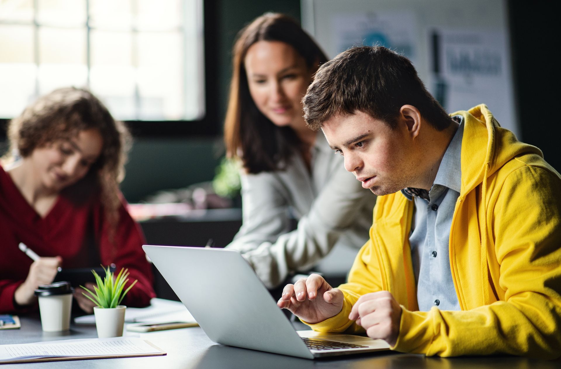 A group of people are sitting at a table using laptops.