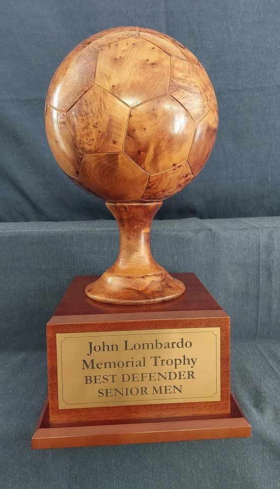 A wooden trophy with a soccer ball on top of it.