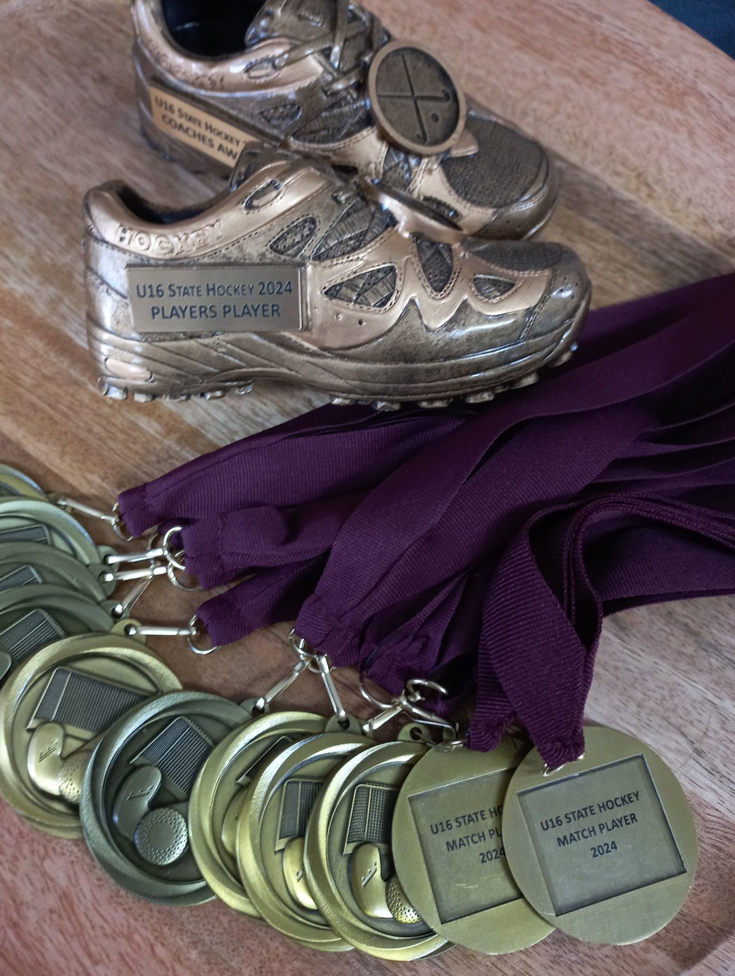 A pair of shoes and medals are on a wooden table.