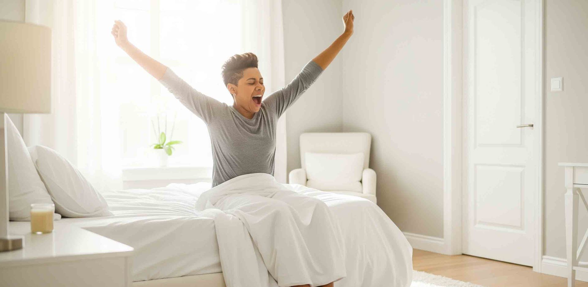 A person waking up with energy, stretching in a bright, clean bedroom.