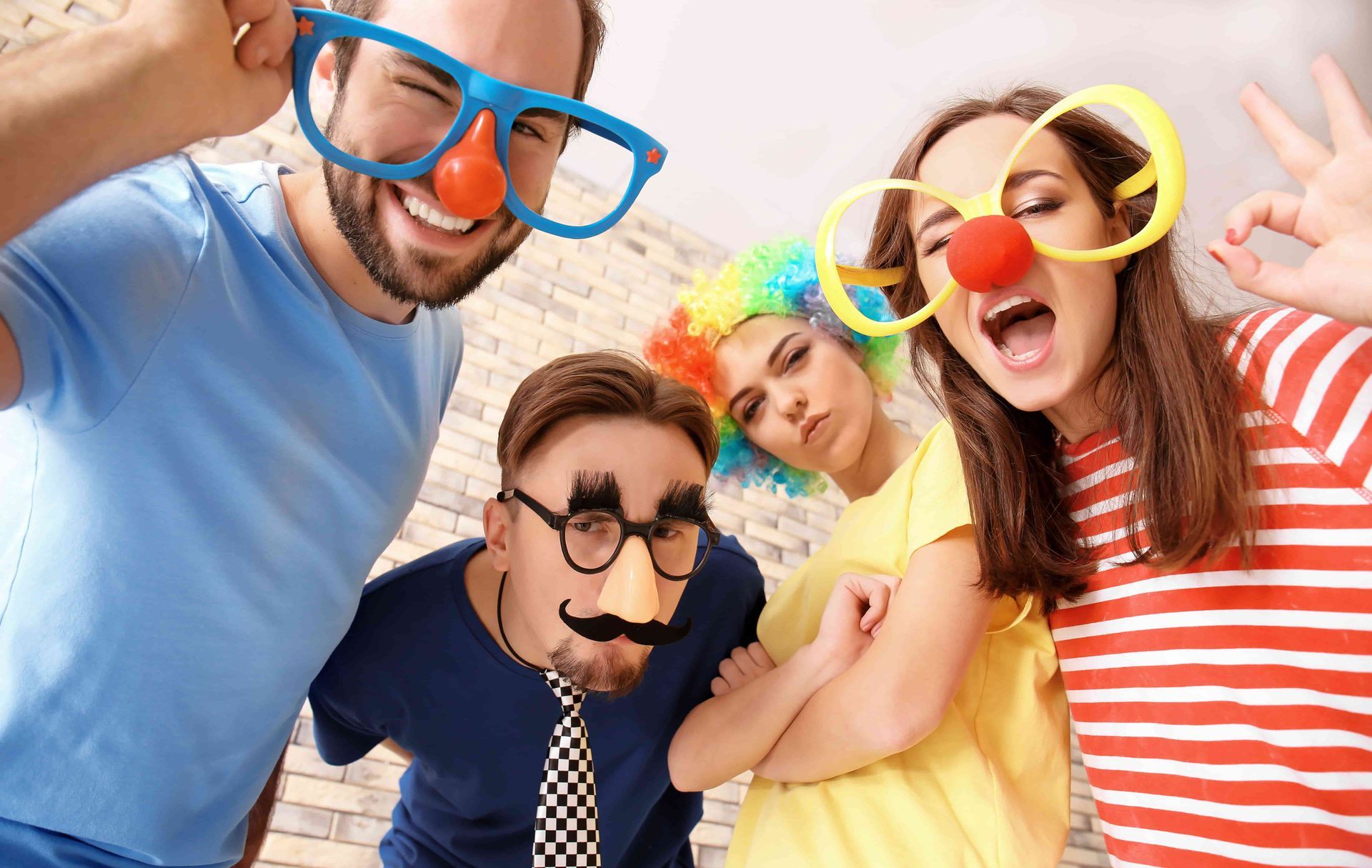 Four Happy People Wearing Funny Glasses and Noses Posing for a Photo Booth