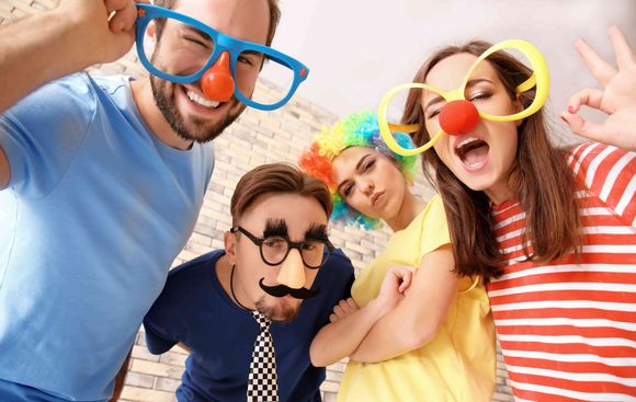 Four Happy People Wearing Funny Glasses and Noses Posing for a Photo Booth