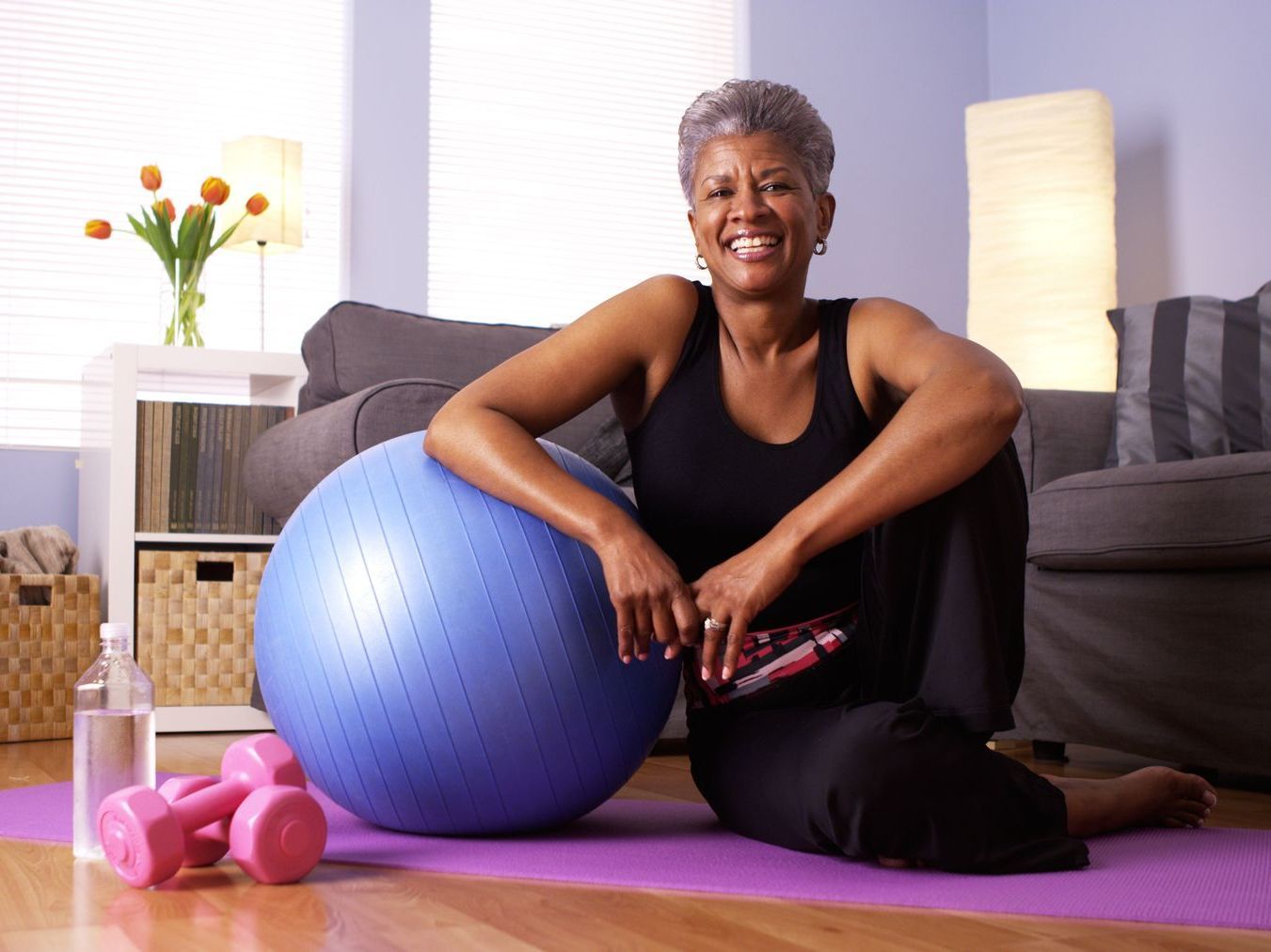 An elderly couple is lifting dumbbells together in a gym.