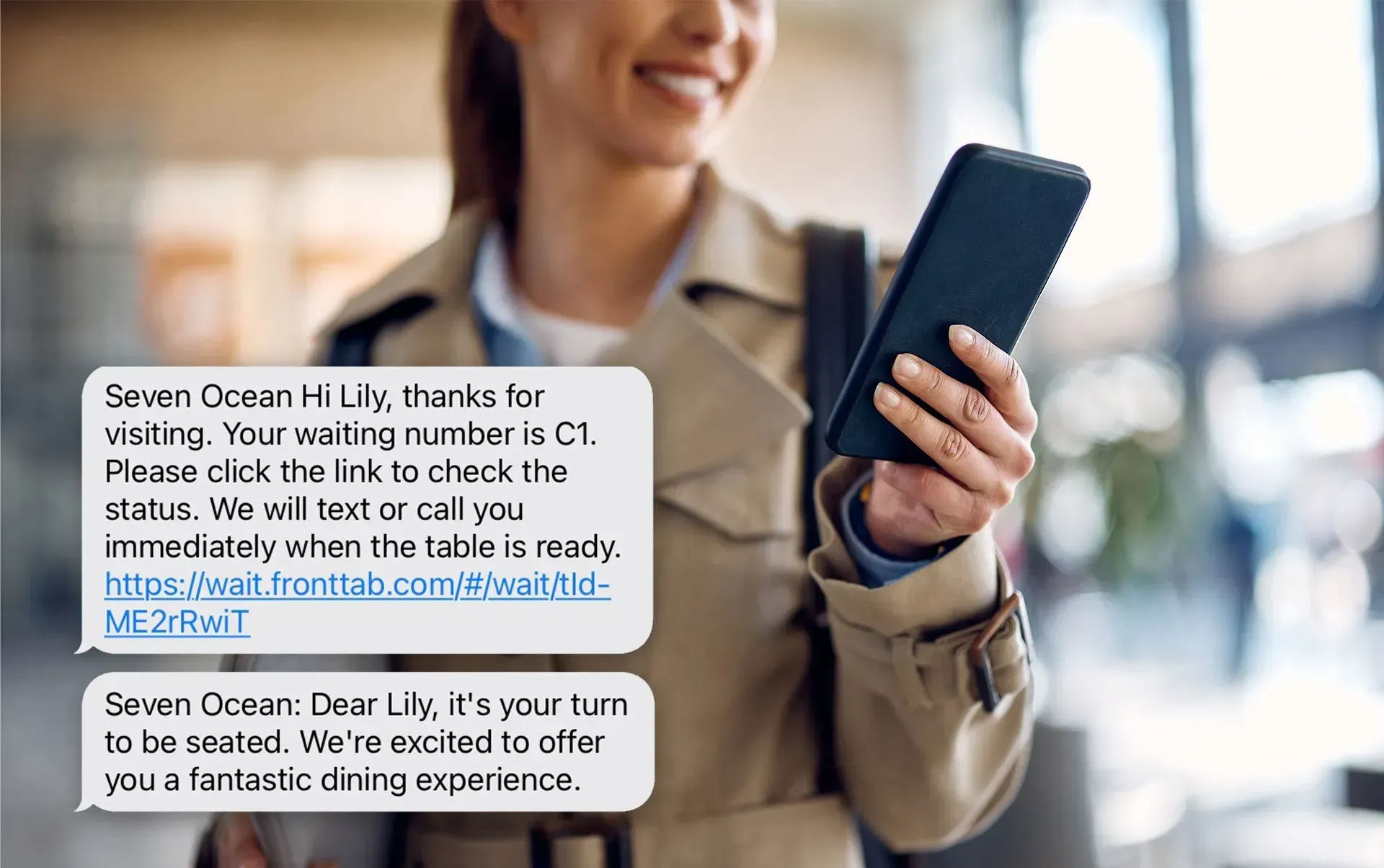 A smiling restaurant customer looks at their phone, which displays a ZBS POS Front Waitlist text notification. The notification includes a friendly greeting, real-time updates about their waitlist status, and a link to check when their table will be ready, enhancing their dining experience with seamless communication.