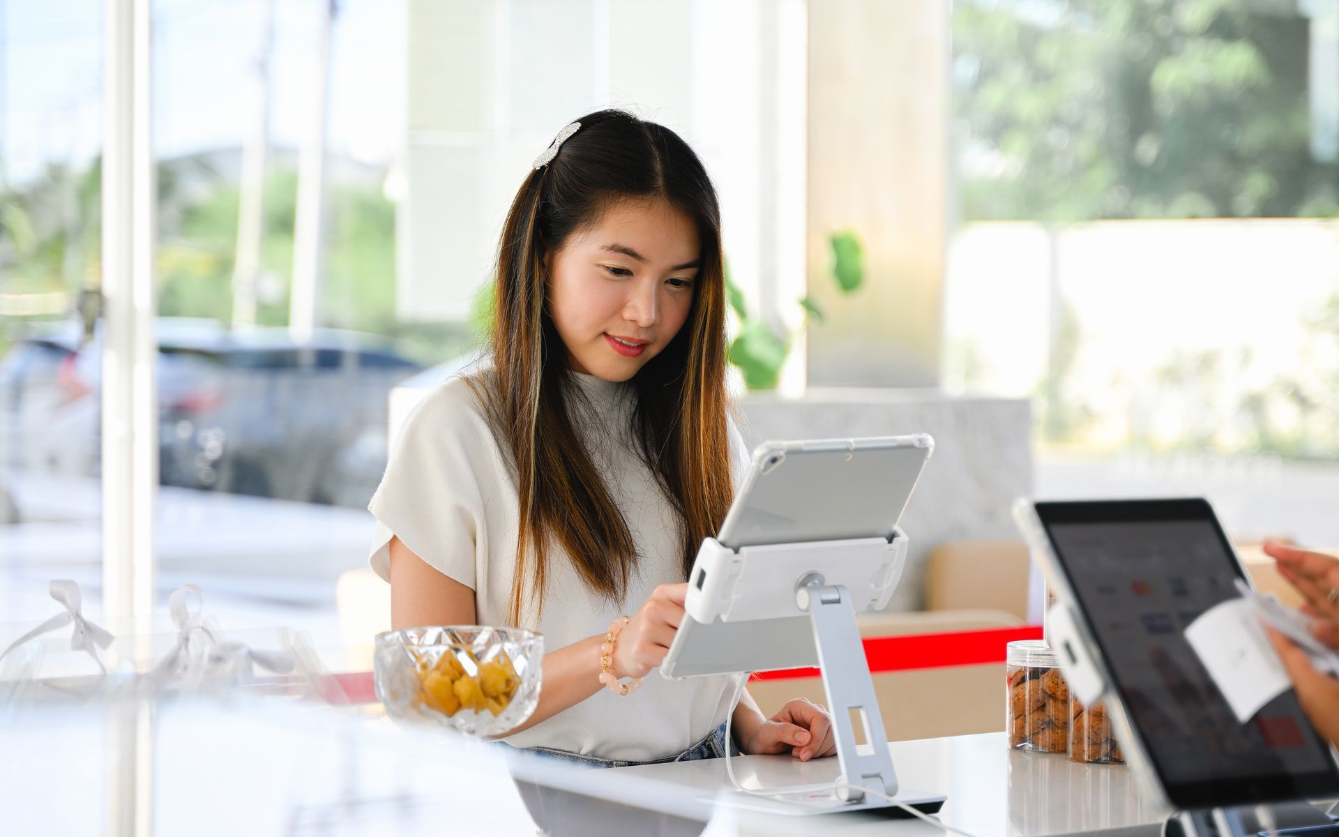 An Asian restaurant customer stands at the host stand, interacting with a ZBS POS Front Waitlist tab