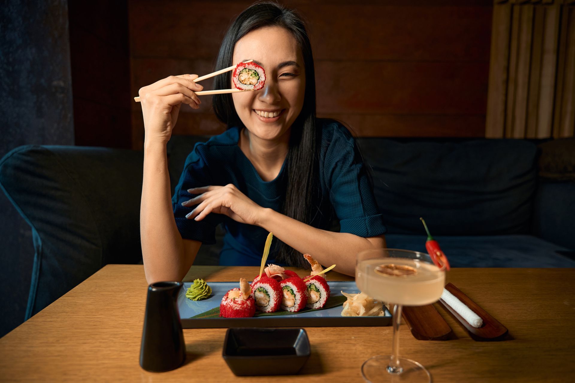 A girl is eating suhi at a sushi restaurant