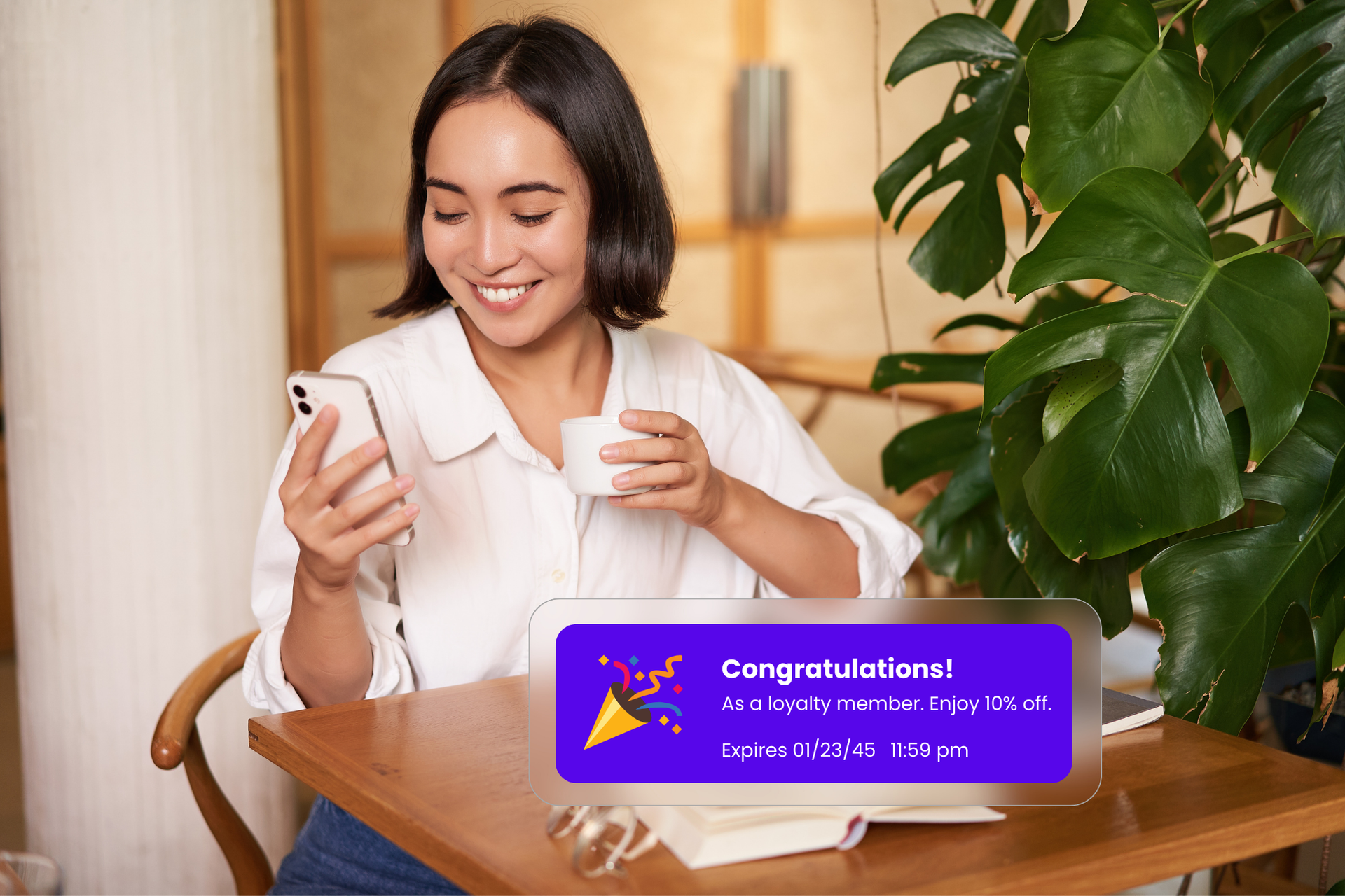 A woman sitting in a café, looking at her phone, receives a text notification about a special marketing deal for being a loyalty member. The message highlights a first-time customer offer.