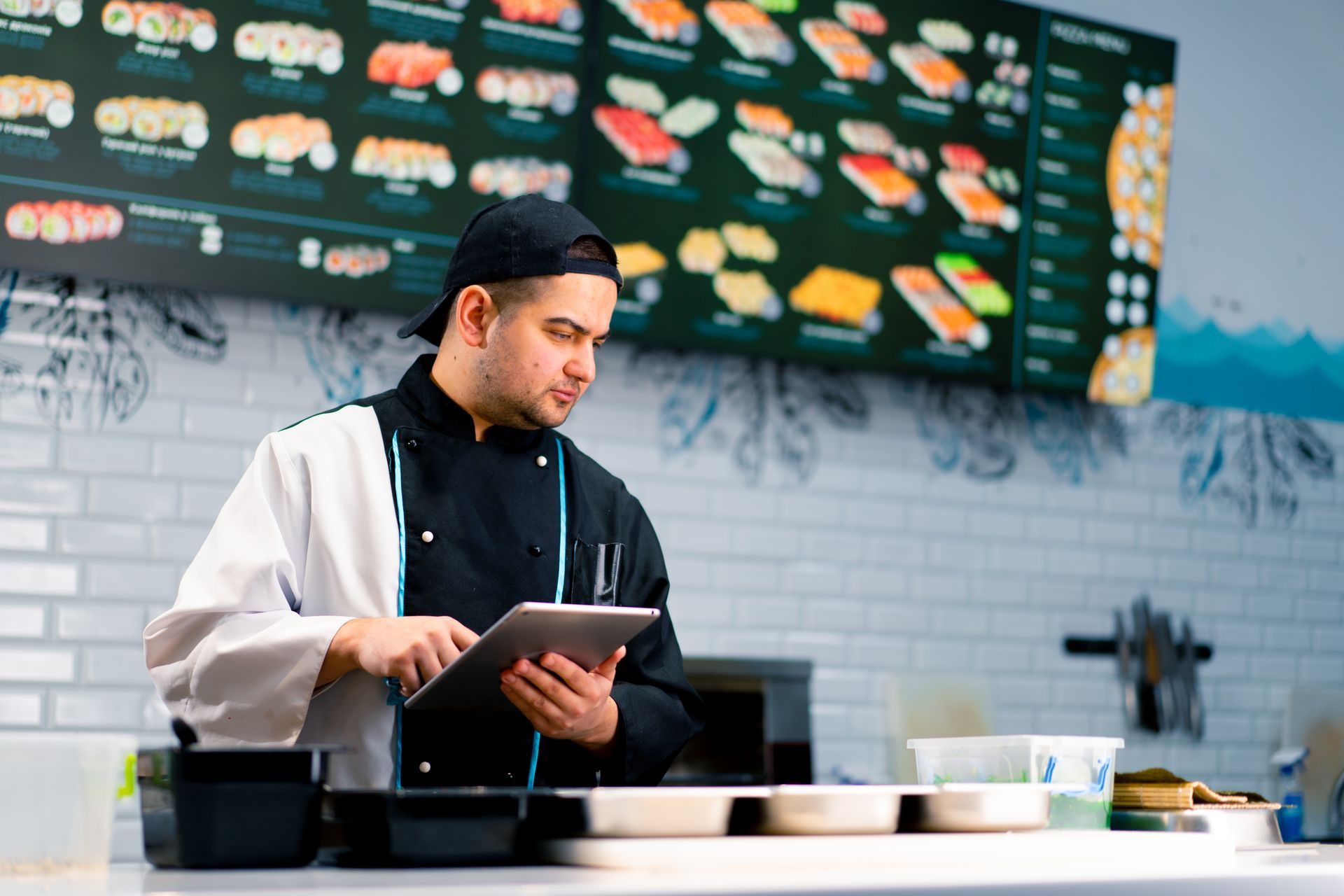 a chef is checking the orders from the online platform at the kitchen of a sushi restaurant
