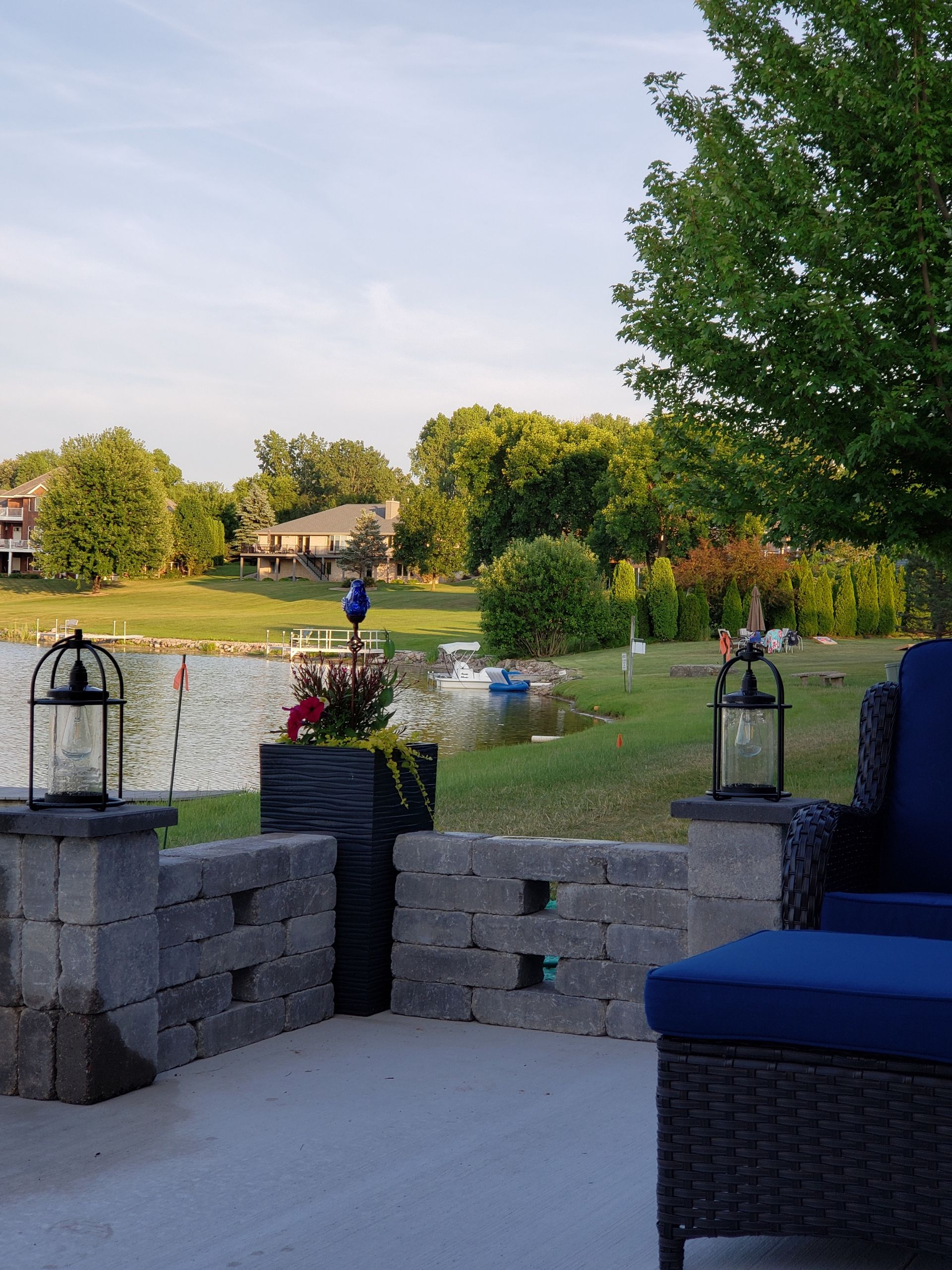 A patio with a chair and ottoman overlooking a lake.