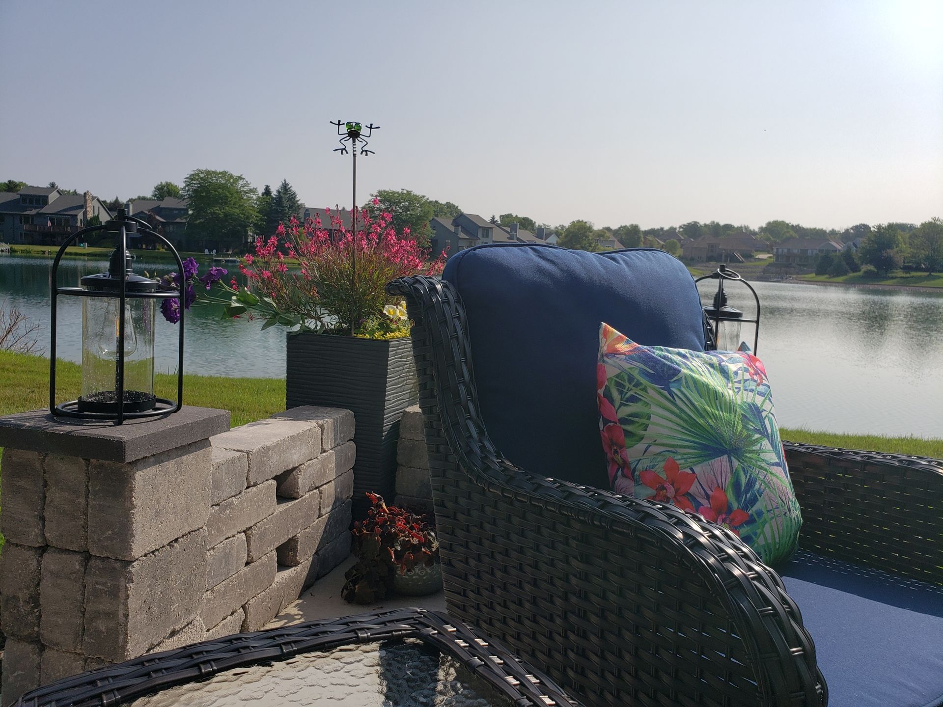A patio with a chair and a table with a view of a lake.