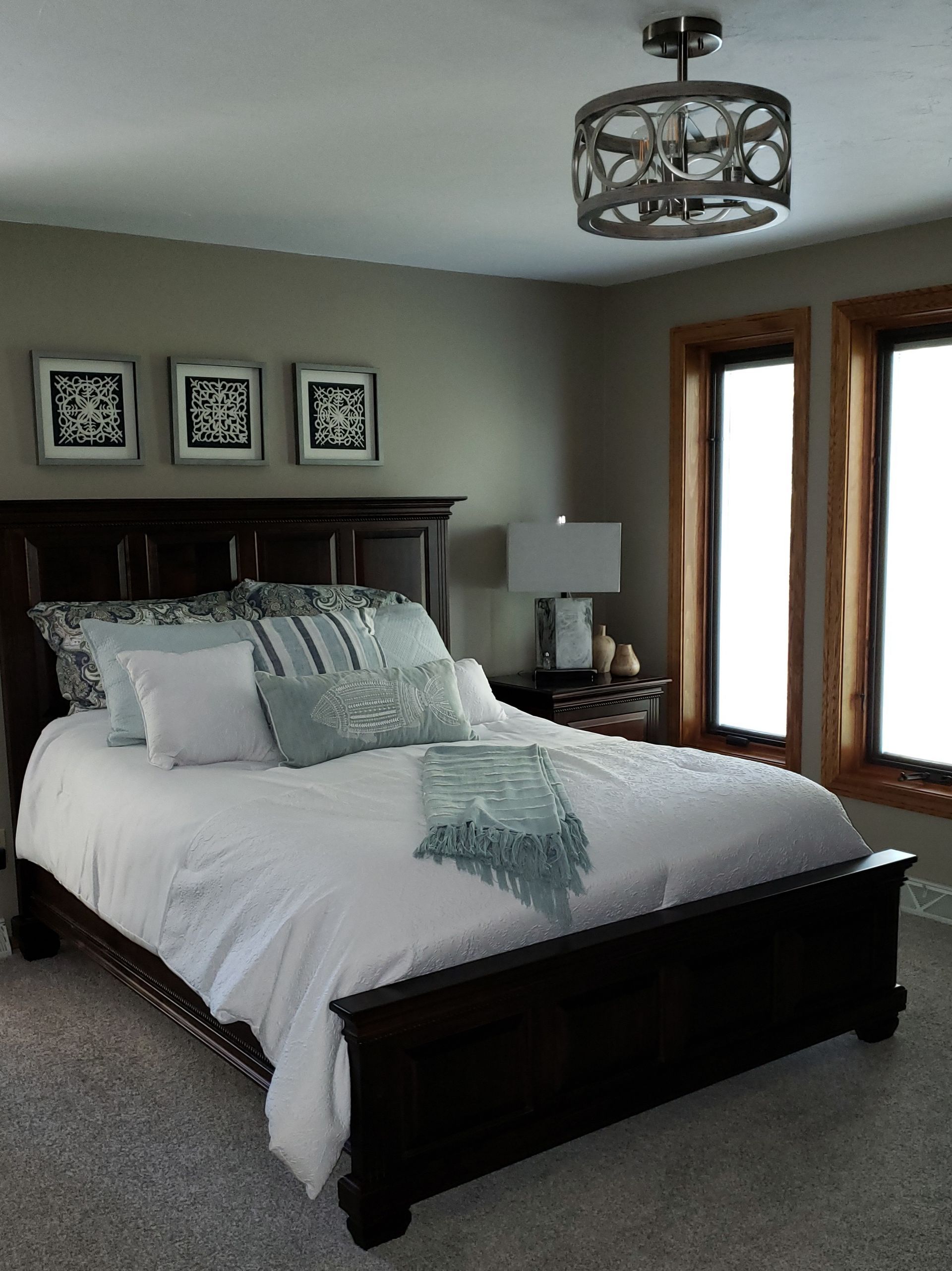 A bedroom with a bed , lamps , and windows.