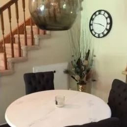 A dining room with a round table and chairs and a clock on the wall.