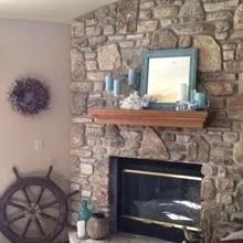 A living room with a stone fireplace and a wooden steering wheel.