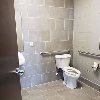 A bathroom with a toilet , sink and mirror.