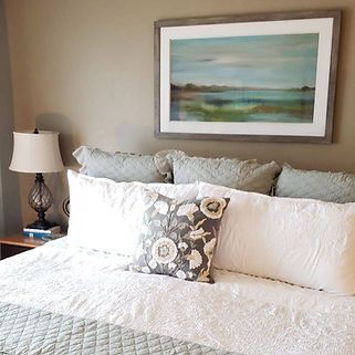 There is a painting on the wall above the bed.