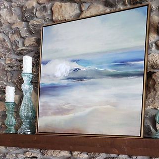 A painting of the ocean is hanging on a mantle next to candles.