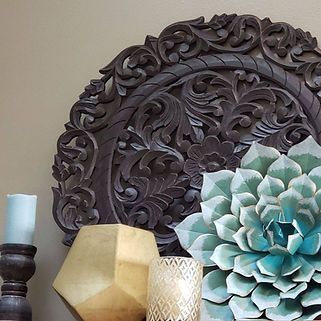 A wooden headboard is sitting on a table next to a vase and candles.