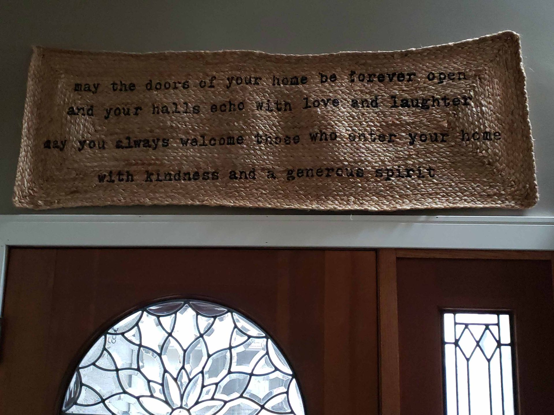 A welcome mat is above a door with a stained glass window.