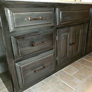 A bathroom vanity with gray cabinets and drawers and a marble counter top.