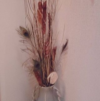 A vase filled with dried flowers and peacock feathers.