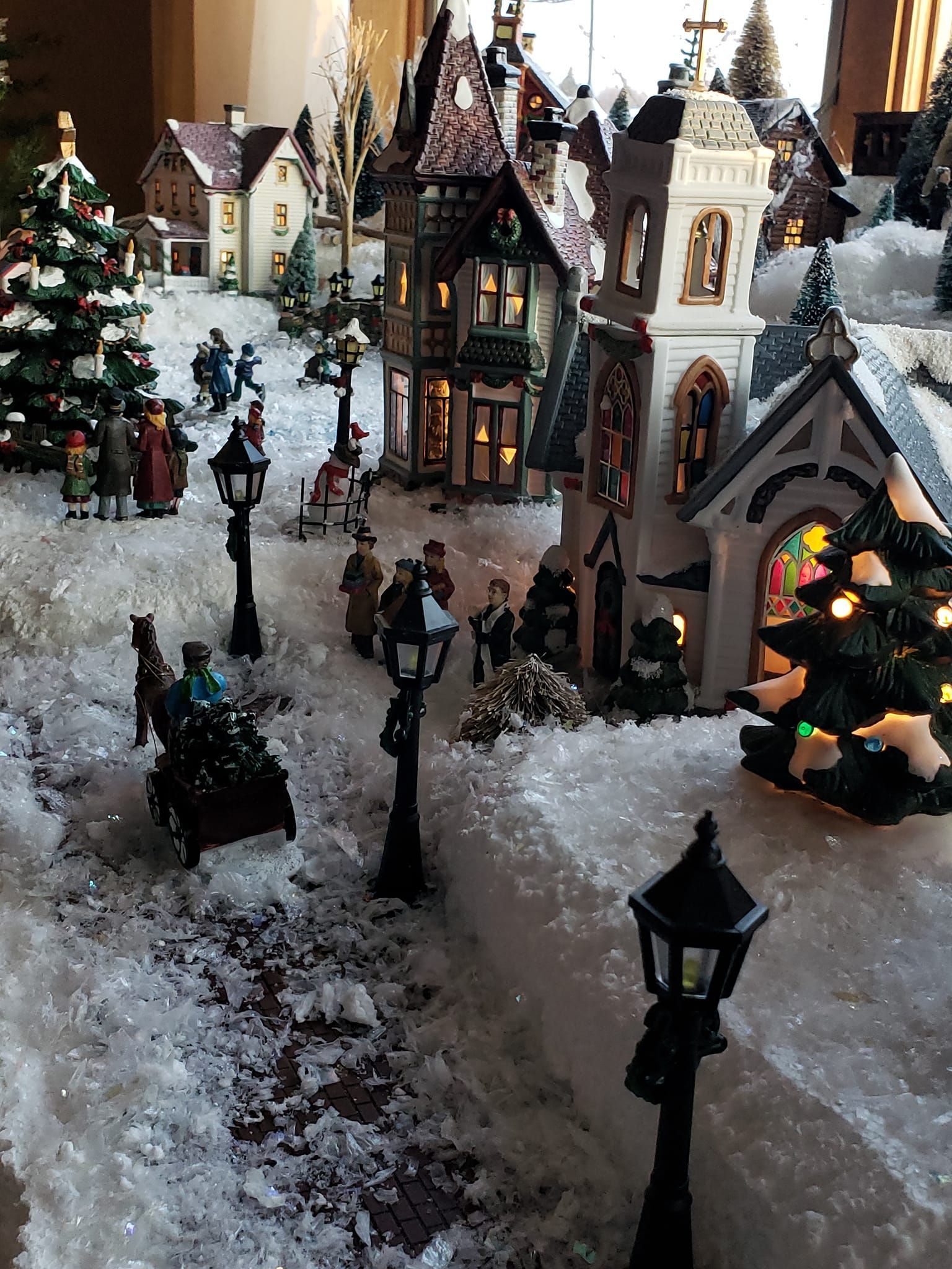 A christmas village with a church and a clock tower in the snow.