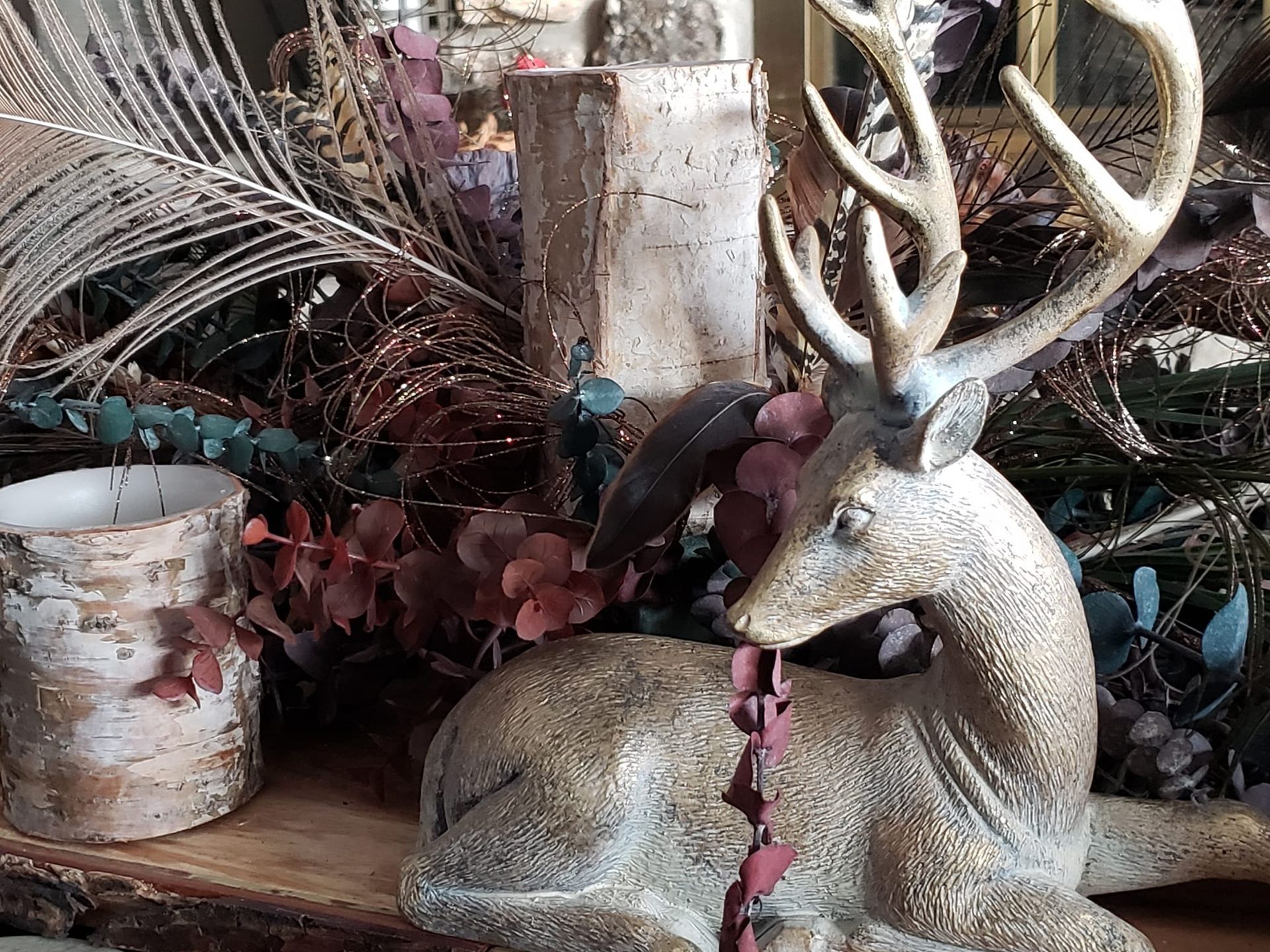 A statue of a deer with antlers is sitting on a wooden table.