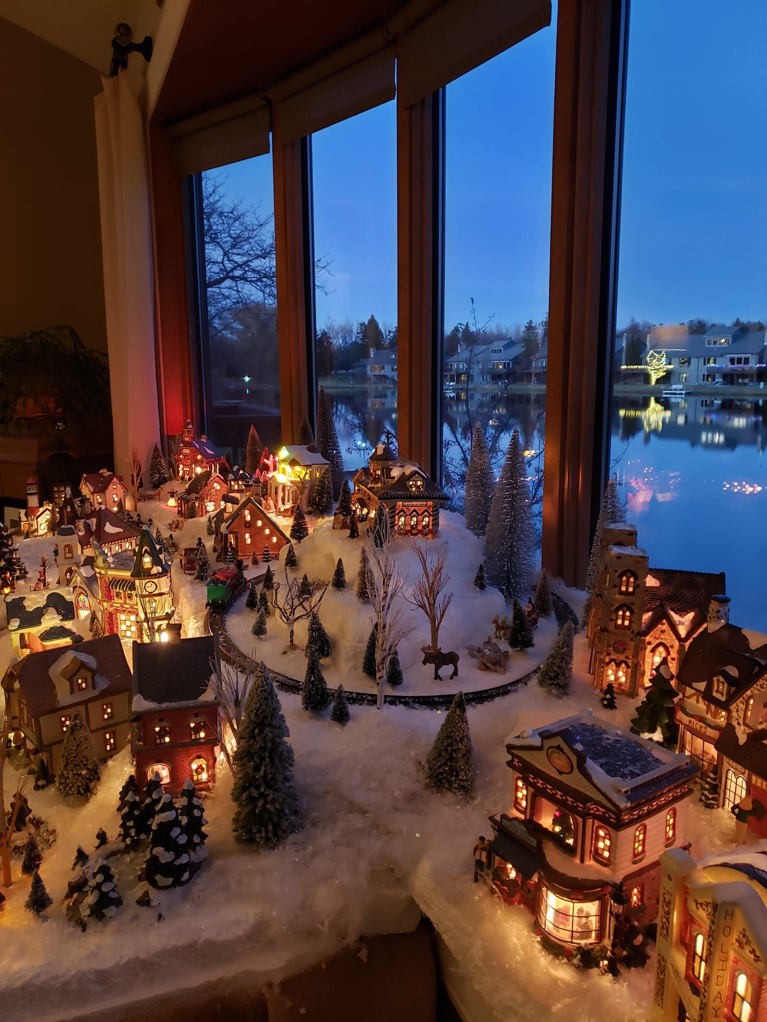 A christmas village is sitting in front of a window.