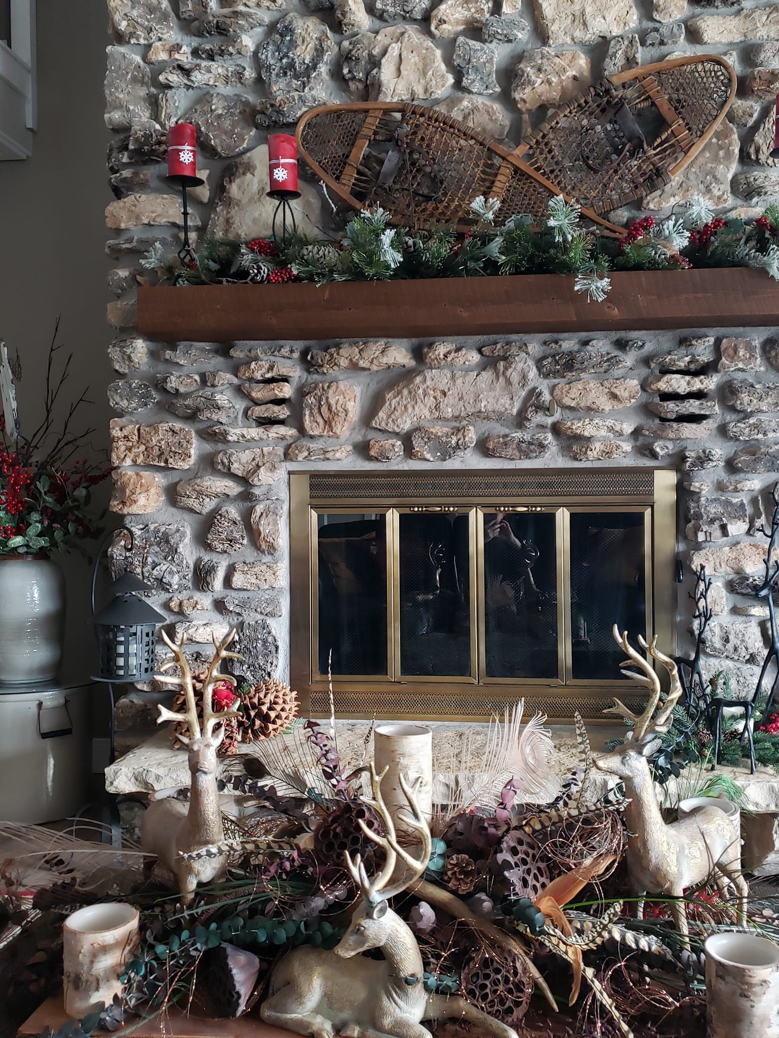 A living room with a stone fireplace decorated for christmas.