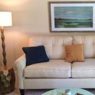 A living room with a couch , lamp , table and painting on the wall.