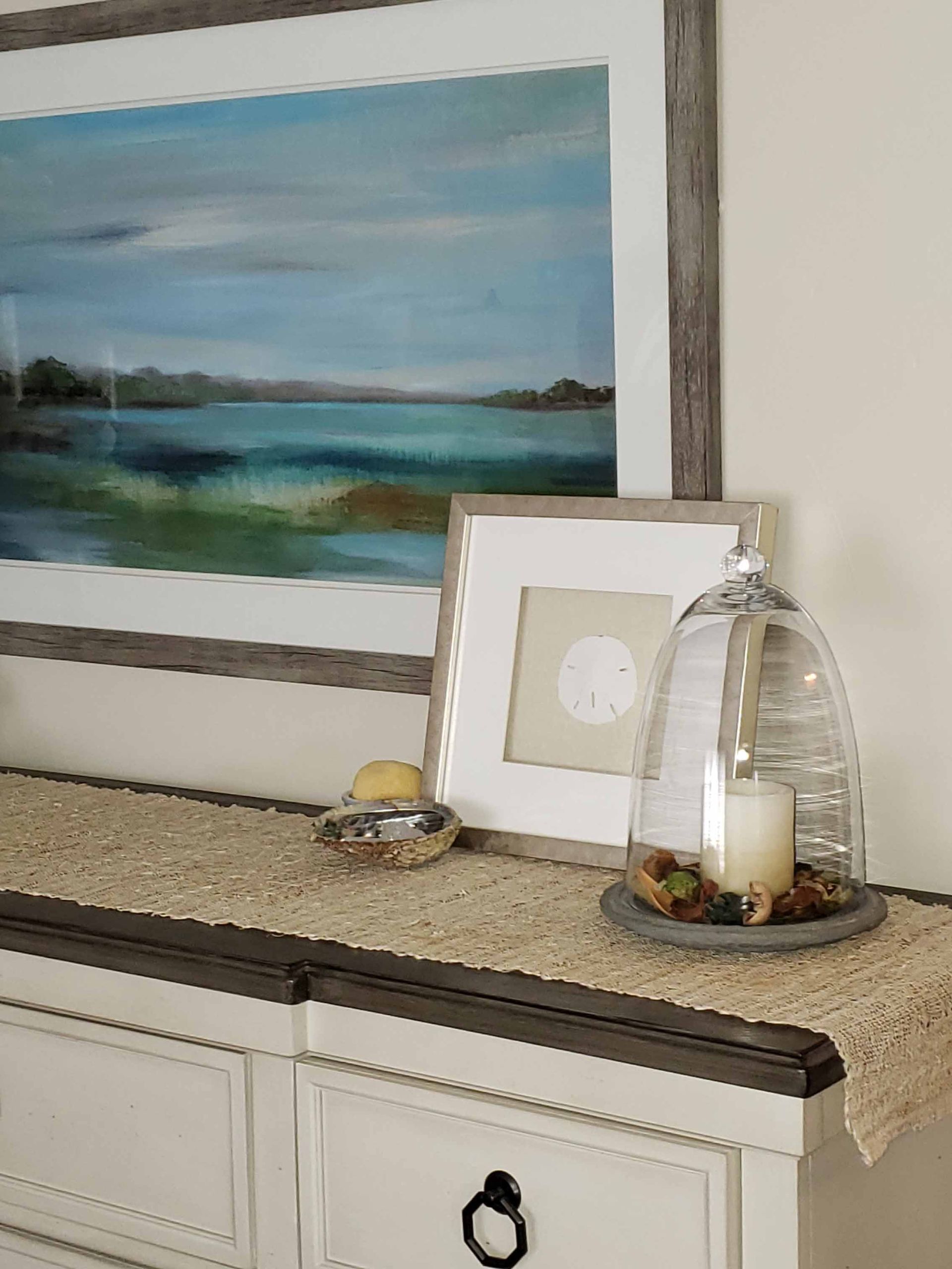 A dresser with a picture on it and a candle on it