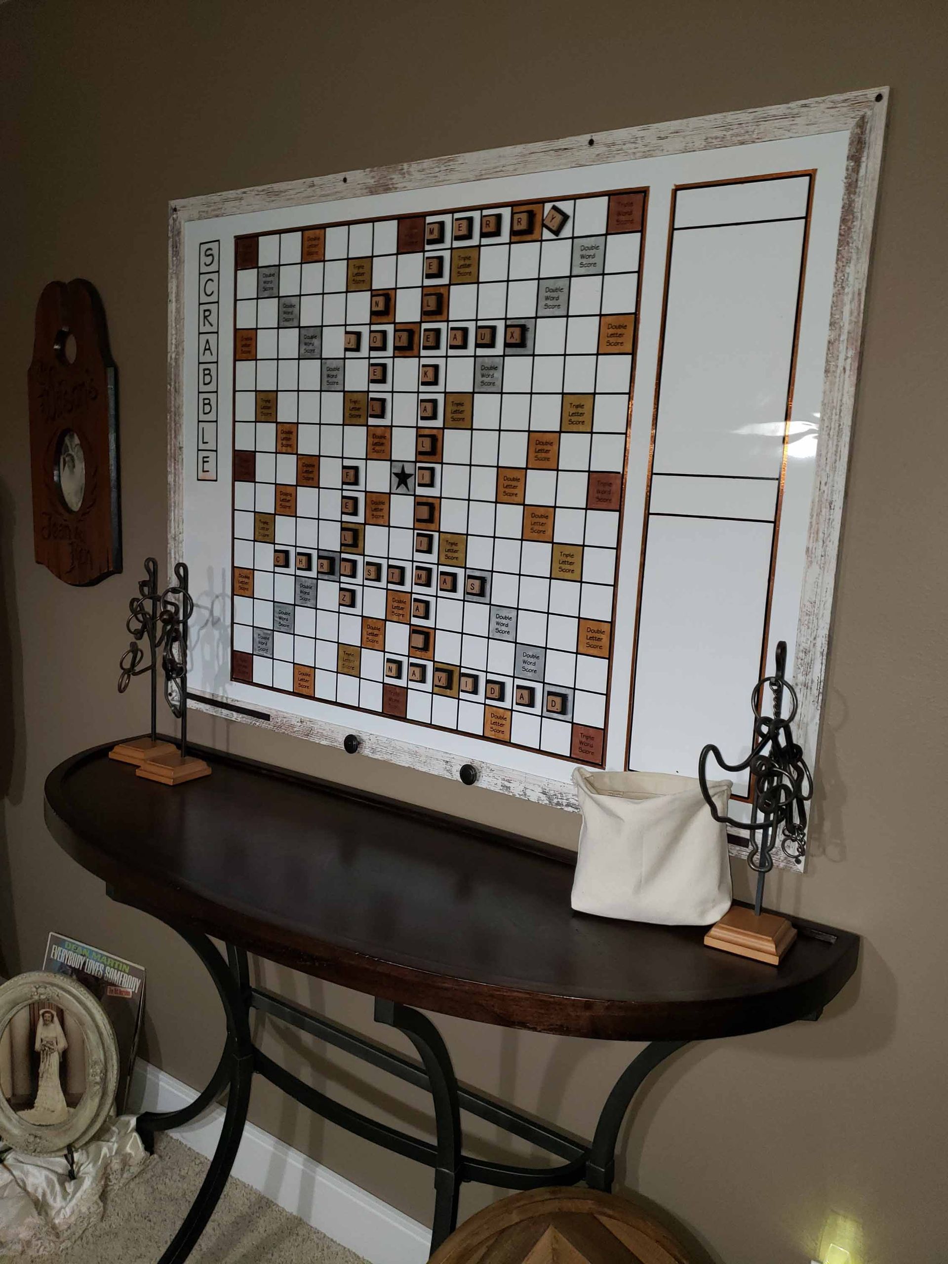 A chess board is hanging on a wall above a table.