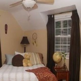 A bedroom with a bed , nightstand , lamp and ceiling fan.