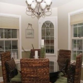 A dining room with wicker chairs , a table , and a chandelier.