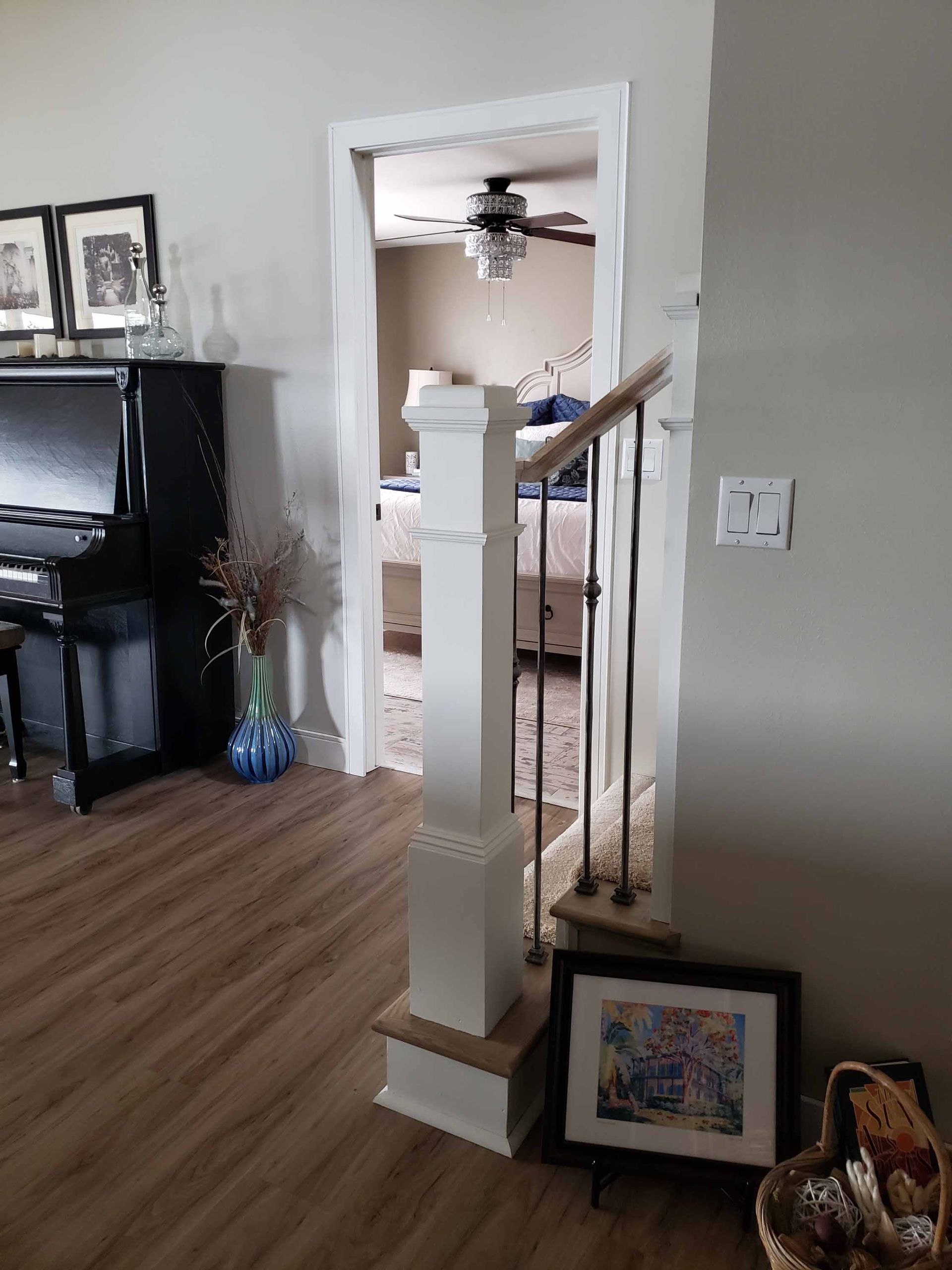 A living room with a piano and stairs leading to a bedroom.