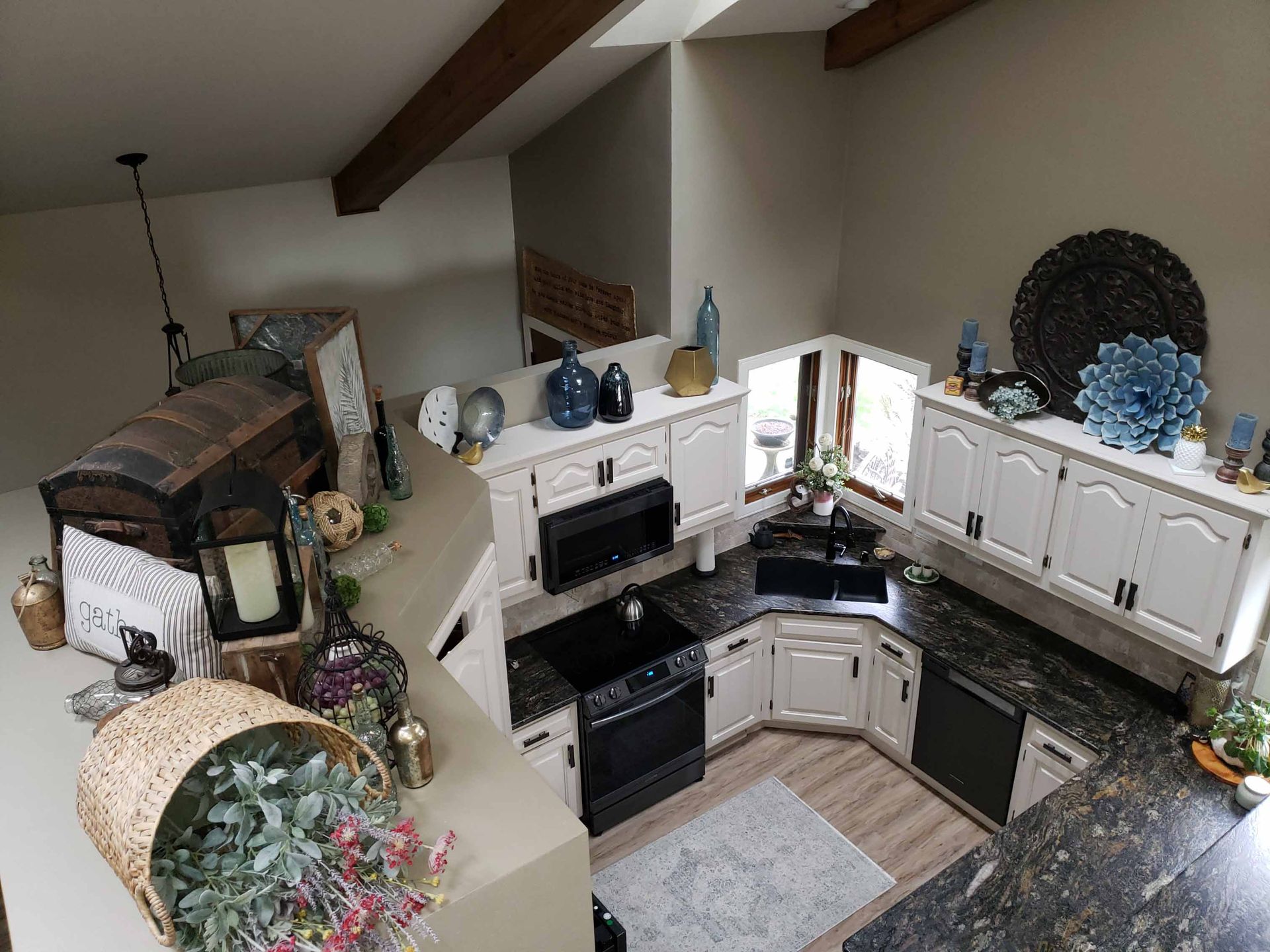 An aerial view of a kitchen with white cabinets and black counter tops.