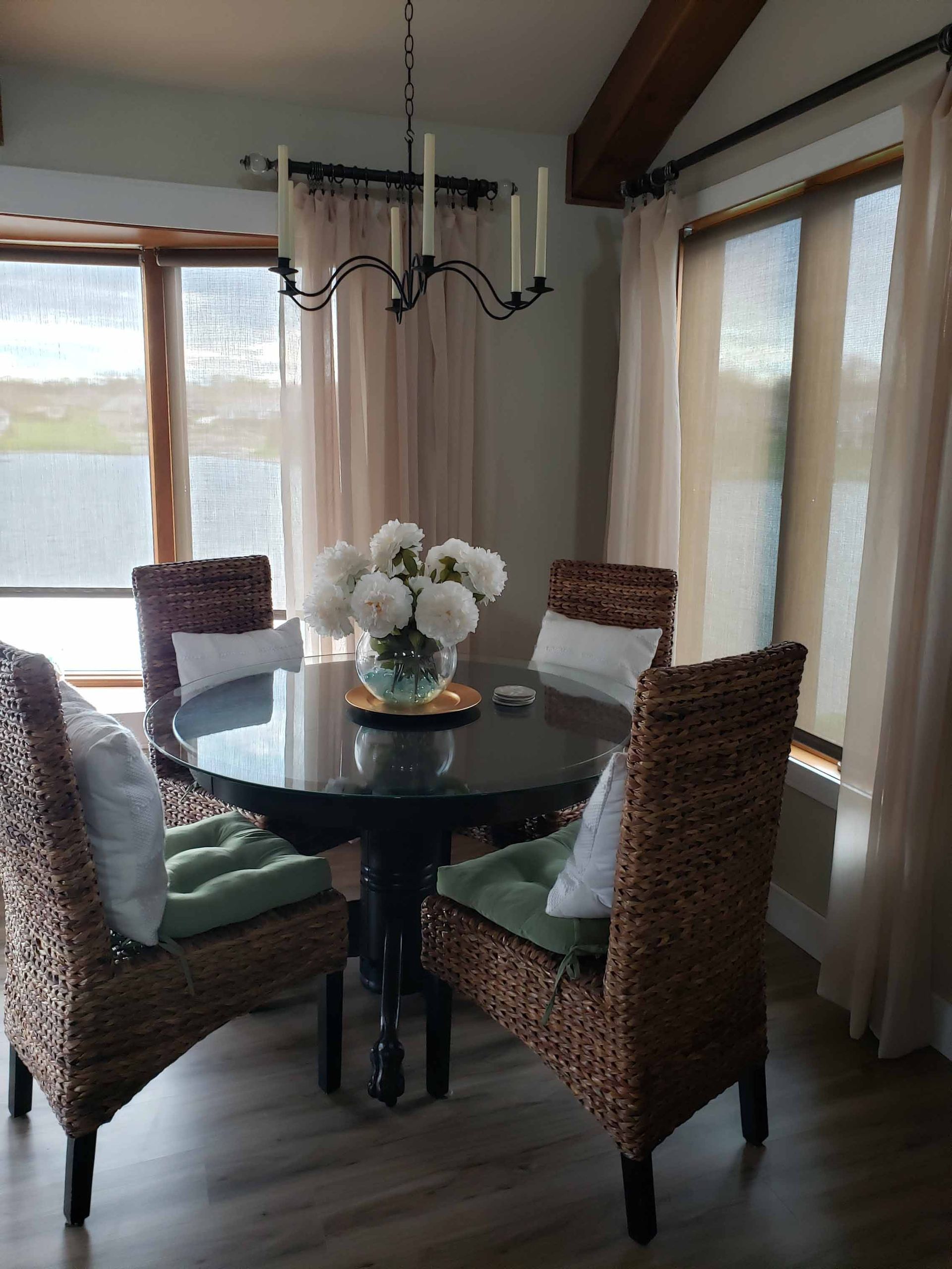 A dining room with a table and chairs and a vase of flowers on the table.
