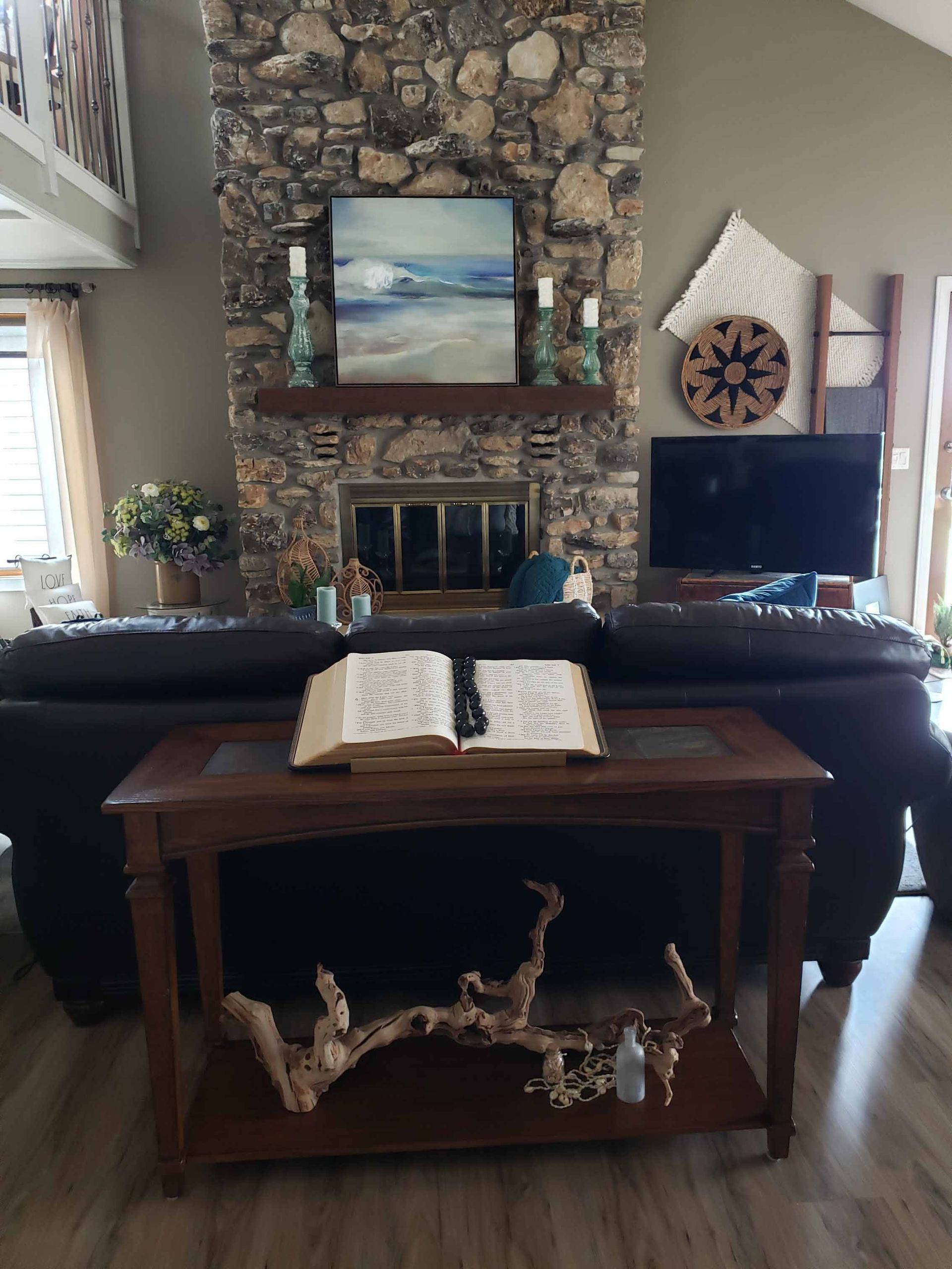 A living room with a bible on a table in front of a fireplace.