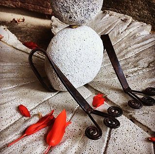 A statue of a bird is sitting on a tiled floor next to a rock.