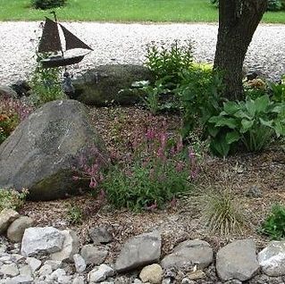 A small sailboat is sitting in the middle of a rock garden.