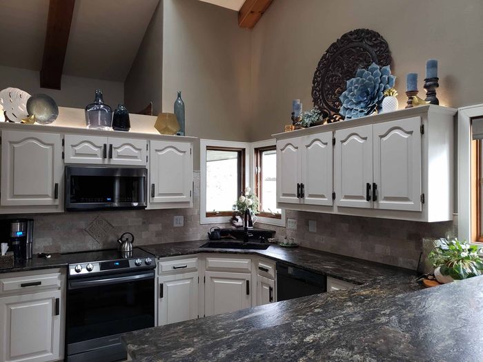 A kitchen with white cabinets and black counter tops