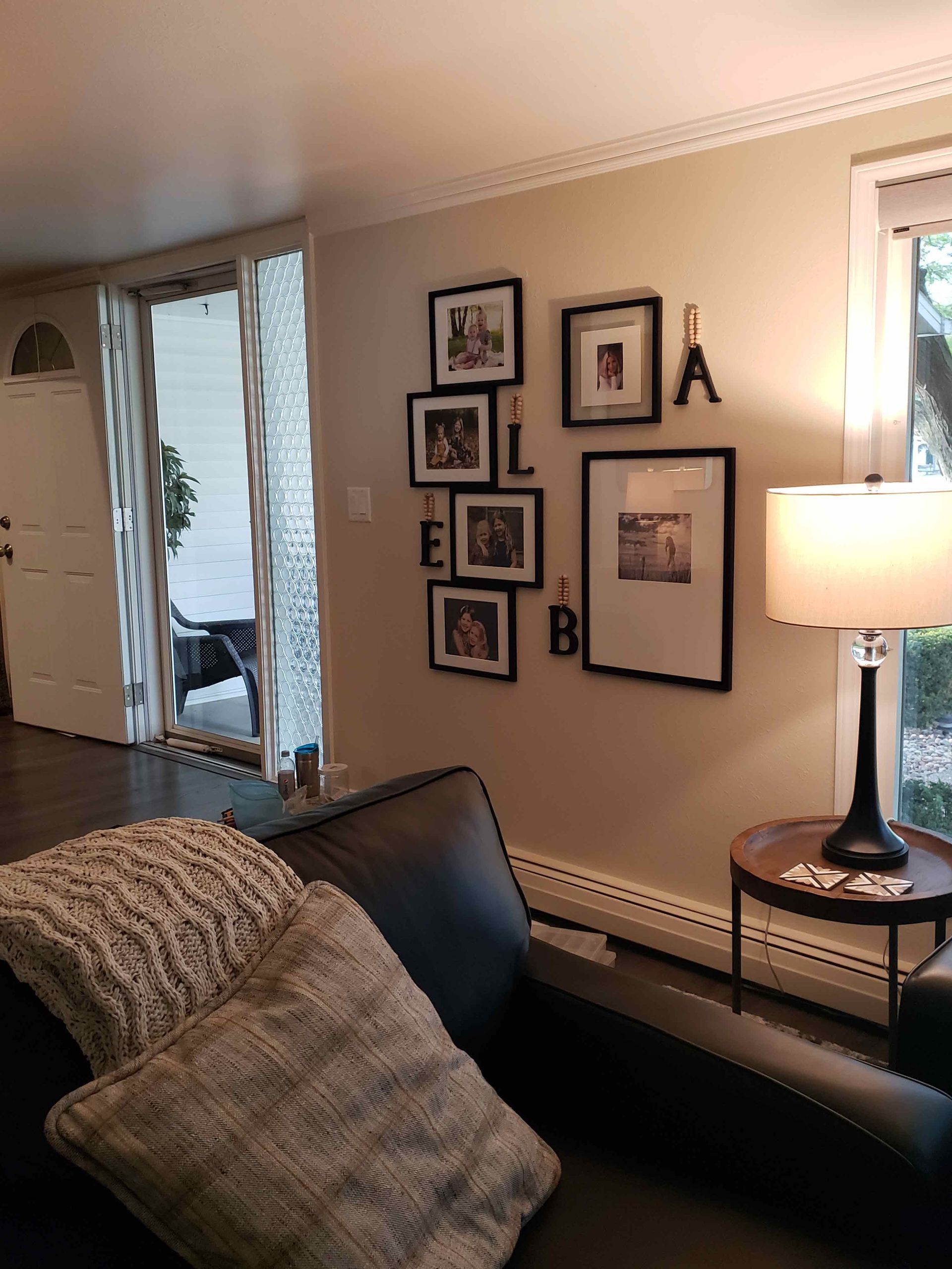 A living room with a couch , table , lamp and pictures on the wall.