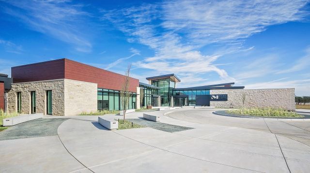 A large building with a lot of windows and a concrete driveway in front of it.