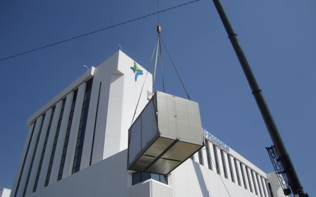 A large white building with a blue star on it is being lifted by a crane