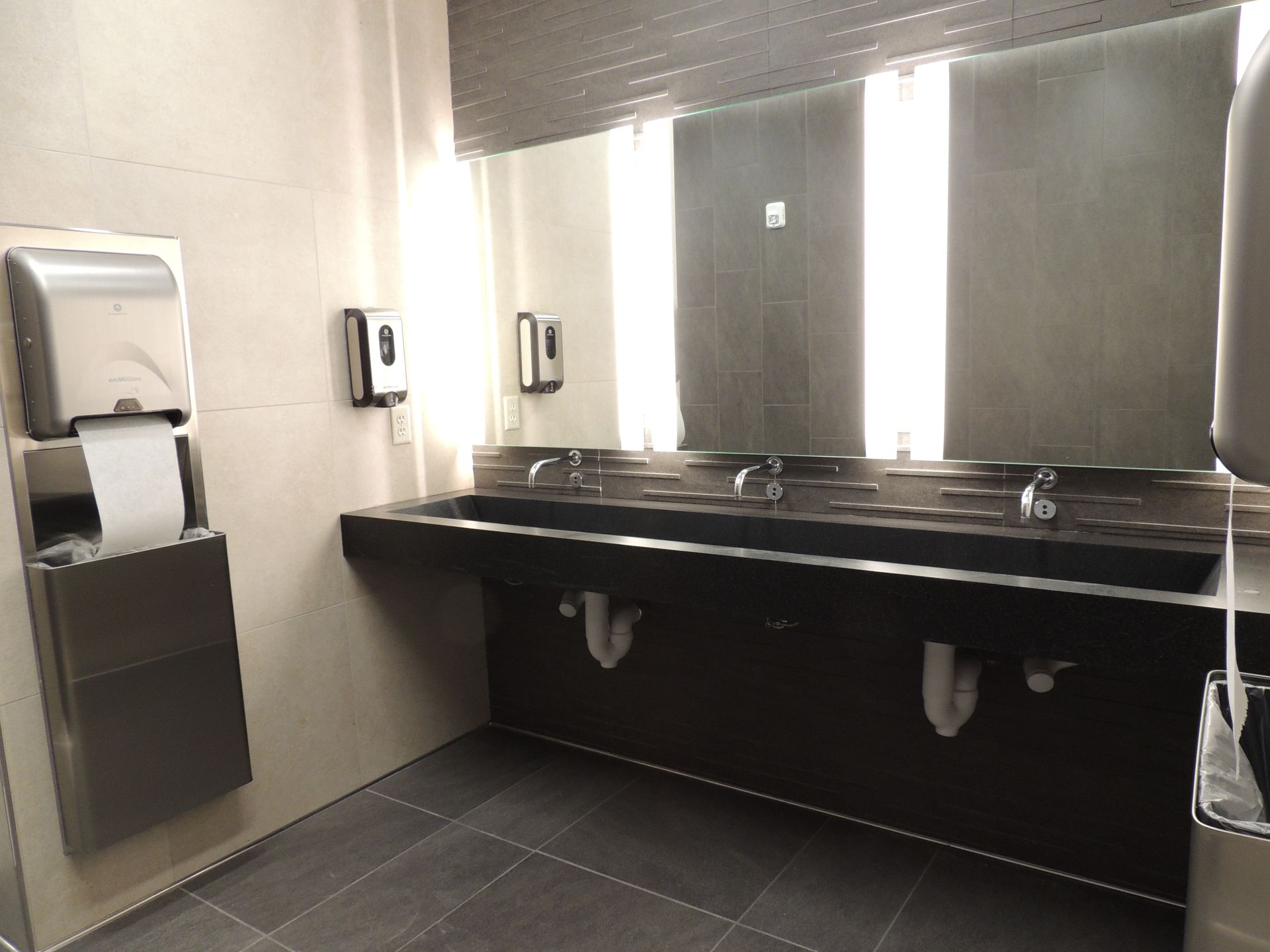 A bathroom with two sinks and a paper towel dispenser