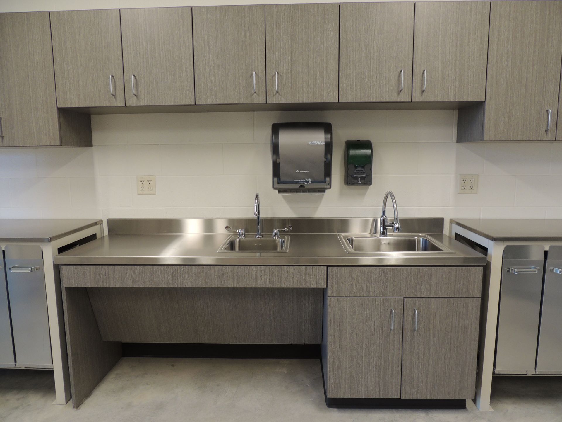 A kitchen with two sinks and a paper towel dispenser