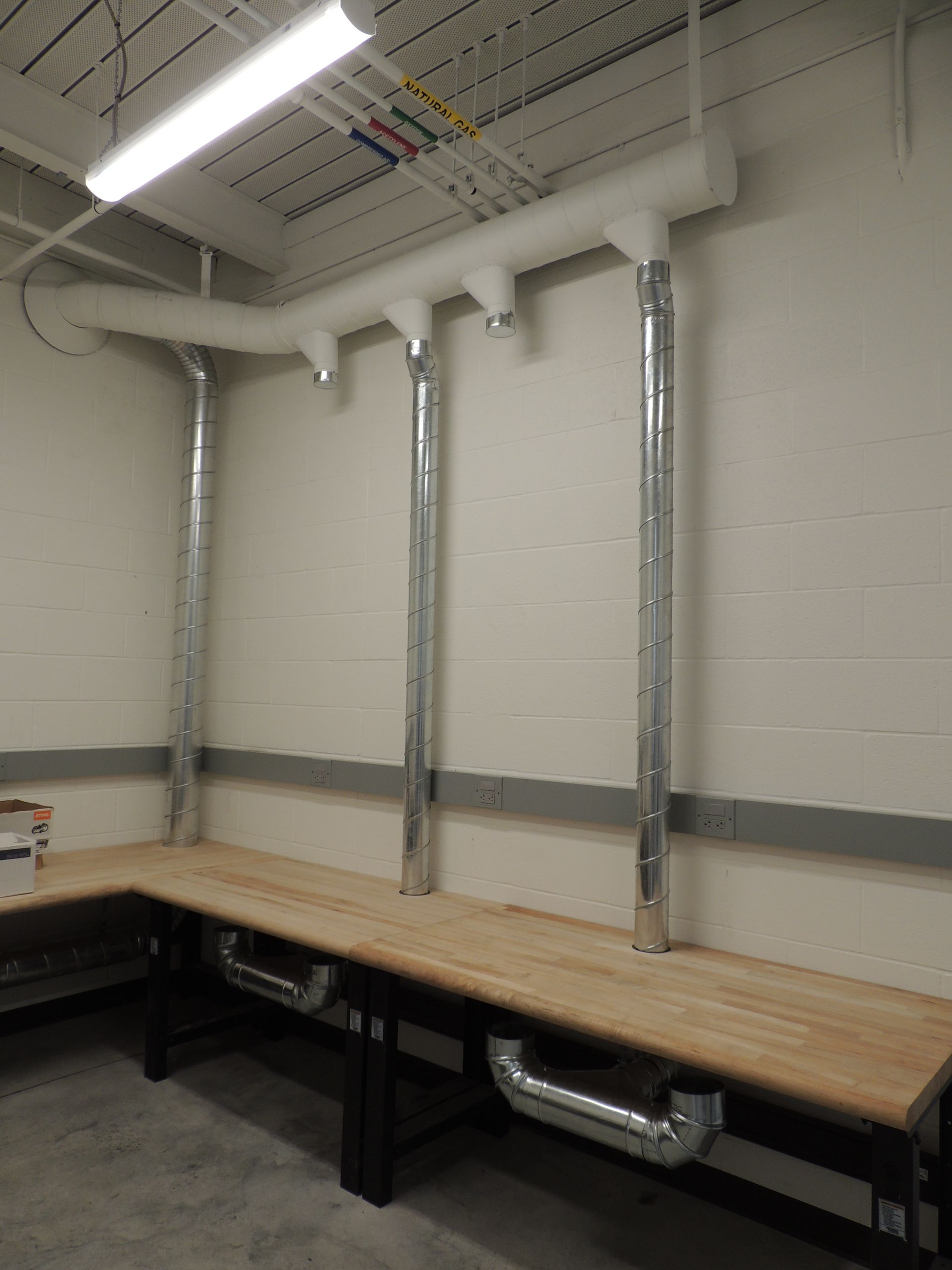 A room with a wooden table and pipes hanging from the ceiling