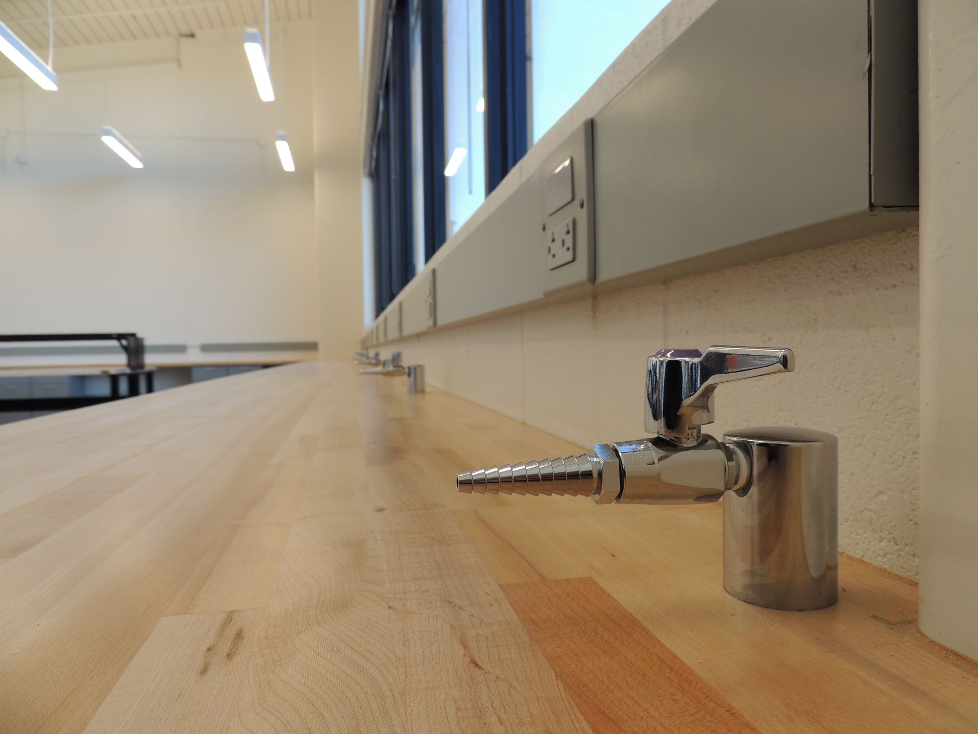 A faucet is sitting on a wooden counter next to a window.