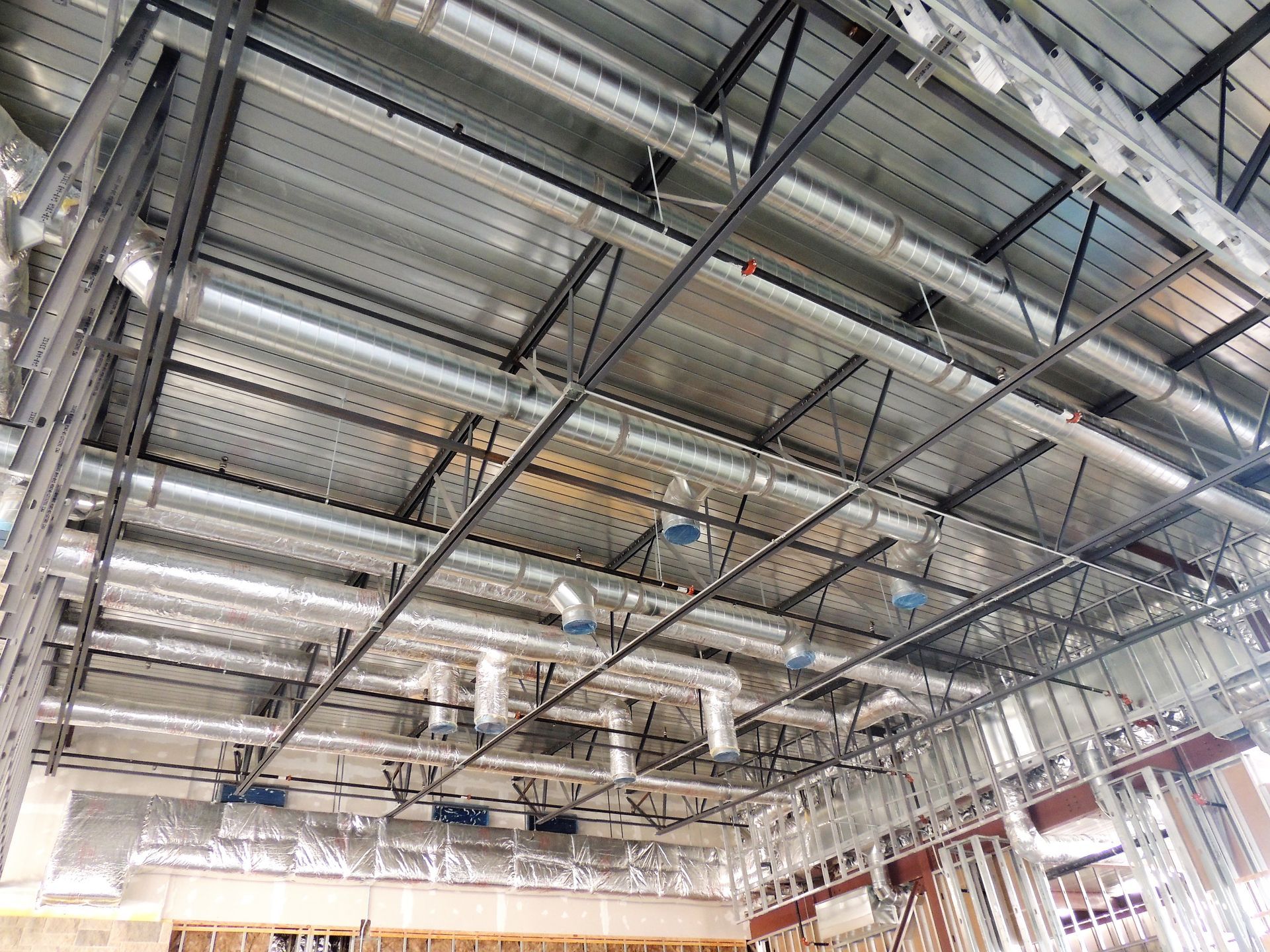 A building under construction with a lot of pipes hanging from the ceiling.